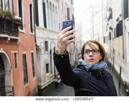 Traveling around the world. European cities. Beautiful modern woman making selfie. Local sights in the background.