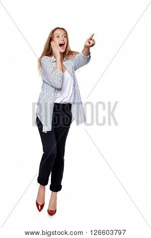 Happy excited woman in full length pointing to the side at blank copy space, over white background