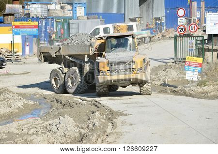 Dolny Hricov Slovakia - April 13 2016: Dirty heavy Volvo dumper loaded by rock moving in work site. There is slovak highway labeled 