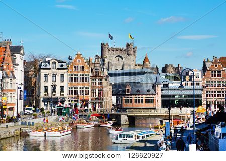 Ghent, Belgium - April 12, 2016: View of old colorful traditional houses along the canal, boats, Gravensteen castle, people walking in popular touristic destination Ghent, Belgium.