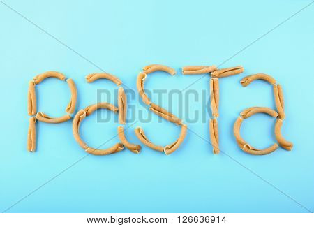 Pasta word made of casarecce on turquoise background