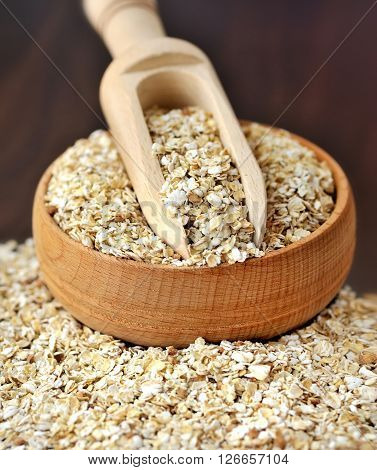 Oatmeal Or Oat Flakes In Bowl And Scoop On Dark Wooden Table