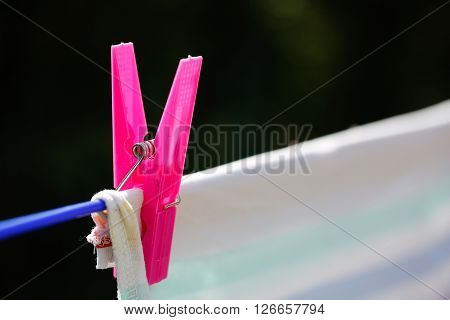 Clothespin holding laundry on the drying line drying clothes outside on fresh air wind and sun. Housework family life household natural living and lifestyle concept.