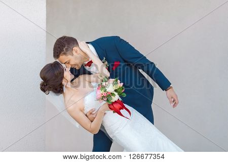 Young wedding couple enjoying romantic moments outside against gray background outdoors