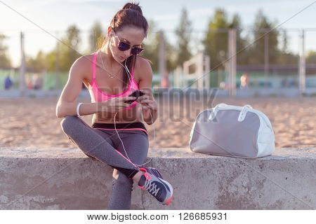 Athlete woman taking picture with smartphone camera, listining music, chatting on the beach summer holidays and vacation healthy lifestyle.