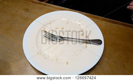 Person finished to eat and put fork on the empty plate. Cafe restaurant casual scene.