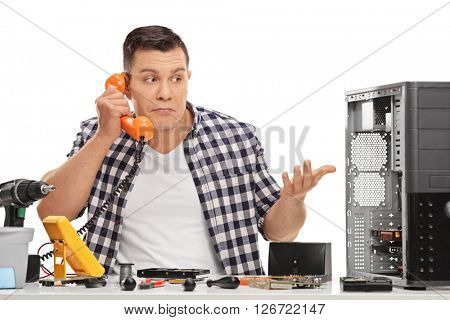 Confused PC technician talking on the phone isolated on white background