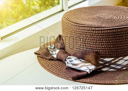 The brown woman hat on white table near the window with daylight. Vacation concept.