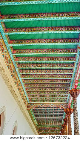 KOKAND UZBEKISTAN - MAY 6 2015: The wooden canopy of the Jami Mosque with colorful islamic patterns and carved capitals of the wooden pillars on May 6 in Kokand.
