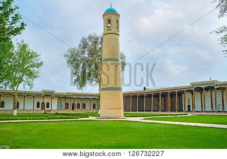 KOKAND, UZBEKISTAN - MAY 7, 2015: The minaret of the Jami Mosque with the iwan and hanaka on the background on May 7 in Kokand, Uzbekistan.