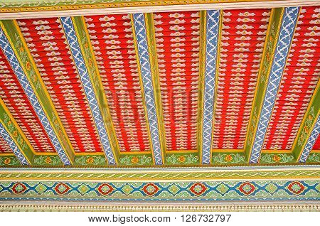 KOKAND UZBEKISTAN - MAY 6 2015: The bright colored ornaments on the carved roof of the open air prayer hall located next to the Damoi Shakhon on May 6 in Kokand.