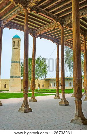 KOKAND UZBEKISTAN - MAY 6 2015: The Jami Mosque minaret seen through the rows of the wooden pillars of its Iwan on May 6 in Kokand.