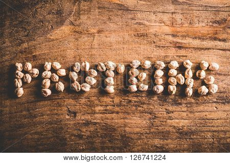 proteins written with chickpeas on wood background