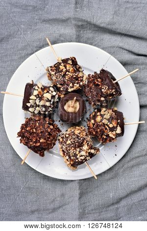 Frozen banana covered with chocolate and peanuts top view