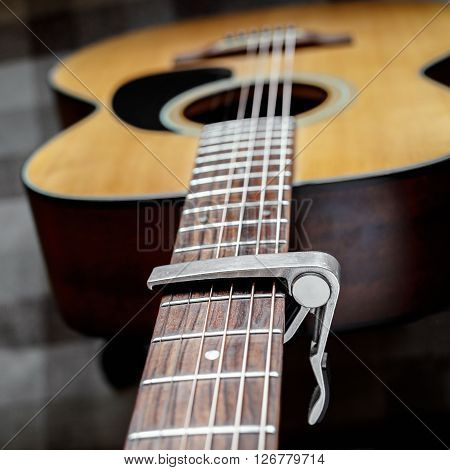 Acoustic guitar neck with a capo, selecive focus