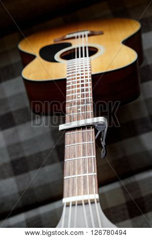 Acoustic guitar neck with a capo, selecive focus