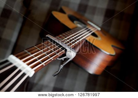 Acoustic guitar neck with a capo, selecive focus