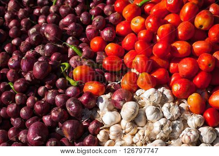 Colourful pile of red Roma tomatoes, purple Spanish onions and white garlic at an outdoor vegetable market in Thimphu, Bhutan