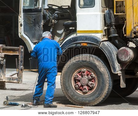 Worker mechanical repairing dirty truck. Service maintenance.