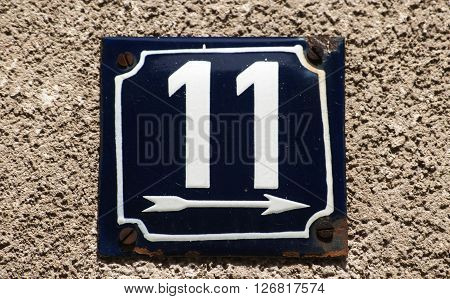 Weathered grunge square metal enameled plate of number of street address with number 11 closeup