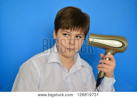 Boy teenager dries hair the hair dryer