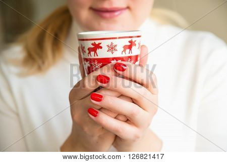 Close up of hands with a cup. Protect your health. Drink herbal tea. Woman holding a red cup of hot drink. Drink hot tea or coffee in the morning cool. Traditional autumn or winter warming drink.