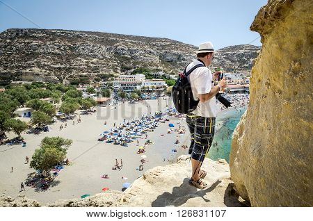 MATALA, CRETE, GREECE - AUGUST 17, 2015: Man stays on cliff and watching onsea bay of Matala town on Crete island, Greece.