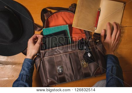 Preparing vintage bag to travel. Men's hands, vintage hat, bag, diary and sungalsses