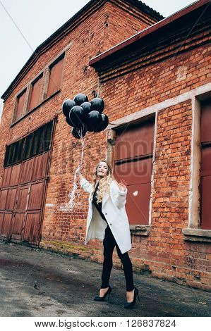 Beautiful girl in fashionable clothes with black balloons