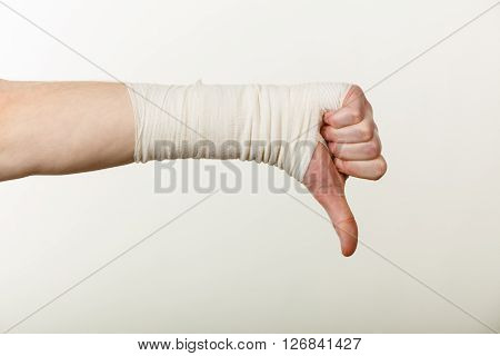 Bad news and information. Medicine aspects. Male hand with bandage showing thumb down sign symbol.
