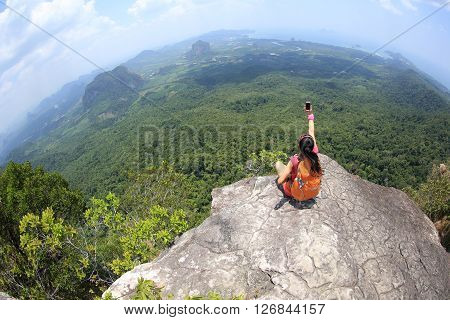 young woman hiker use smartphone taking photo on seaside mountain top
