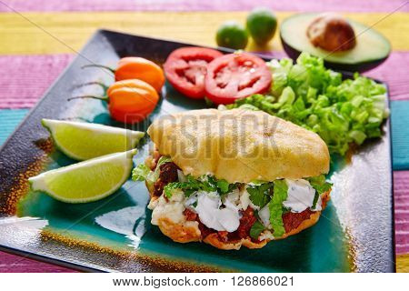 Gordita mexican fried puff corn taco filled with pastor meat lettuce and cream