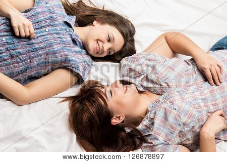 Mother with her daughter lying on the bed and looking at each other.