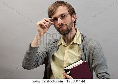 Male student holding books against grey wall background