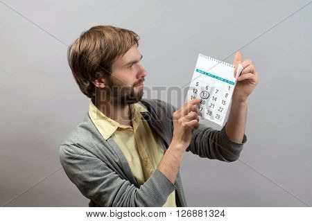 Young man pointing the date on the calendar