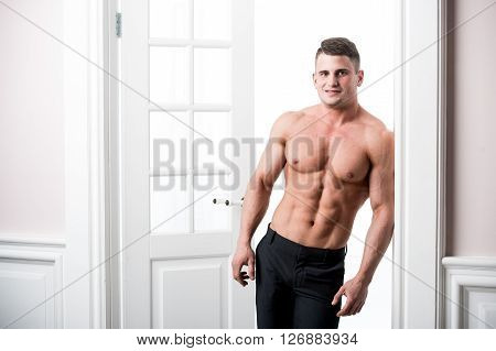 Athlete man standing in the doorway home interior