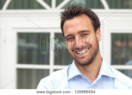 Latin business man smiling outdoors in front of his office