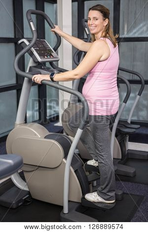 Pregnant woman on crosstrainer at the gym