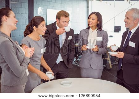 Businesspeople having tea and interacting during breaktime in office