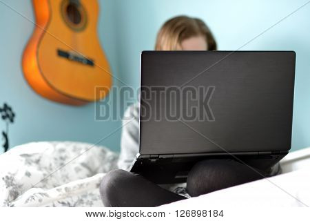 Teen girl on a laptop in her bedroom