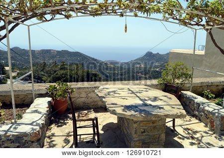 A stone table with two chairs and a view on mountains.