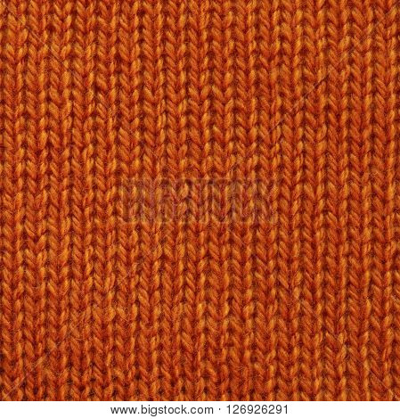 Moderately orange wool knitted fabric texture. Close up fragment of the top view.