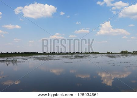 Blue summer sky and reflection of clouds in the surface of the Volga river. Nature landscape view in Russian countryside.