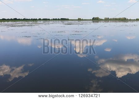 Blue summer sky and reflection of clouds in the surface of the Volga river. Nature landscape view in Russian countryside.