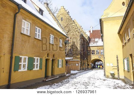 Augsburg Germany - January 17 2016: The Fuggerei and tourists.The Fuggerei is the world's oldest social housing complex still in use. It is a walled enclave within the city of Augsburg Bavaria.