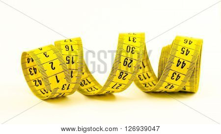 still life with a yellow tape measure and a pencil over white