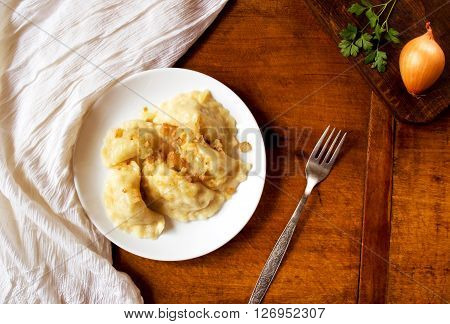 Homemade dumplings with vegetables and greaves on a wooden table