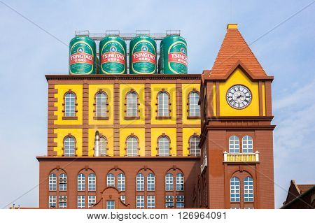 Qingdao China 20/04/2016 Main building of the Qingdao brewery with four cans of beer on the rooftop and a clock tower