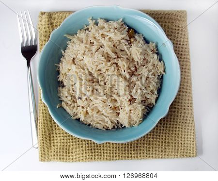 Spicy zeera aromatic Basmati rice in a bowl on wooden background.