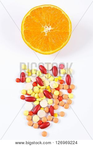 Colorful medical pills tablets capsules or supplements and fresh orange concept of treatment health care and healthy lifestyle